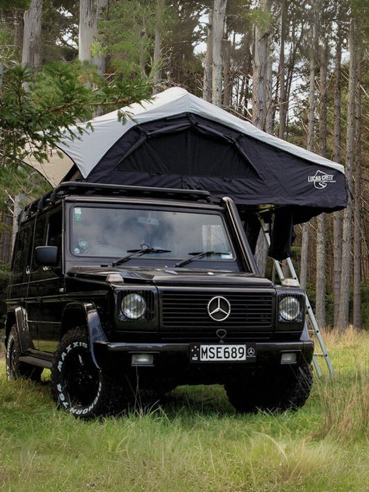A gunmetal grey soft shell roof top tent open on a vehicle. 